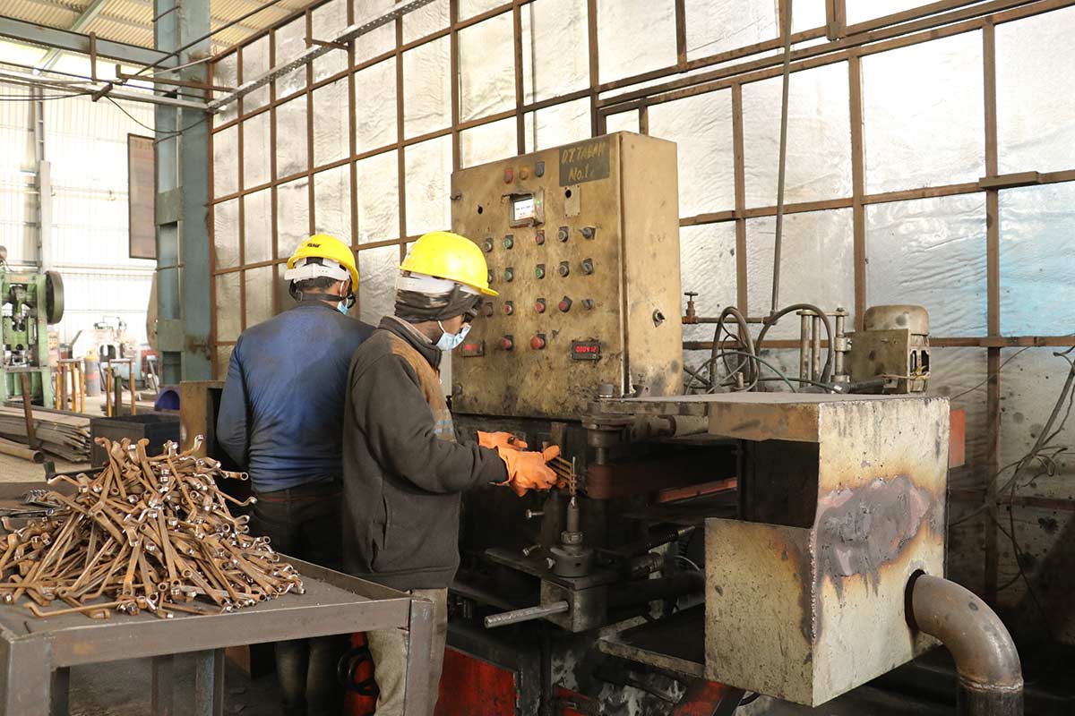 Workers operating hand tool forging equipment